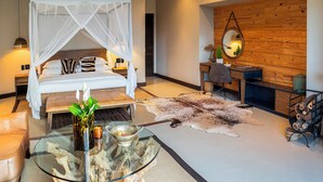 A modern bedroom with a canopy bed, a desk, a mirror, and a leather rug. - Babirwa Game Ranch (Rooiberg)
