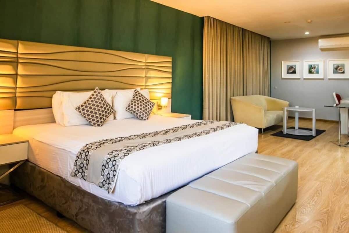 A hotel room with a large bed, a bedside table, a chair, and a small table.