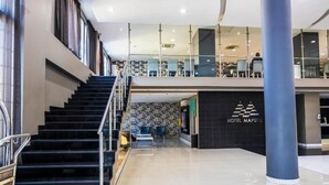 A hotel lobby with a staircase, a reception desk, and a view of the upper floor. - WL Hotel Maputo City Center (Maputo)