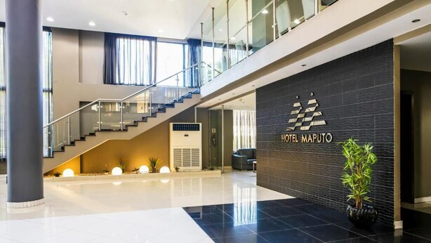 A modern hotel lobby with a staircase, a reception desk, and a large potted plant. - WL Hotel Maputo City Center (Maputo)