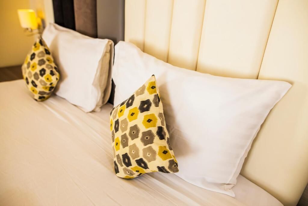 Una cama con dos almohadas, una lisa y otra estampada.