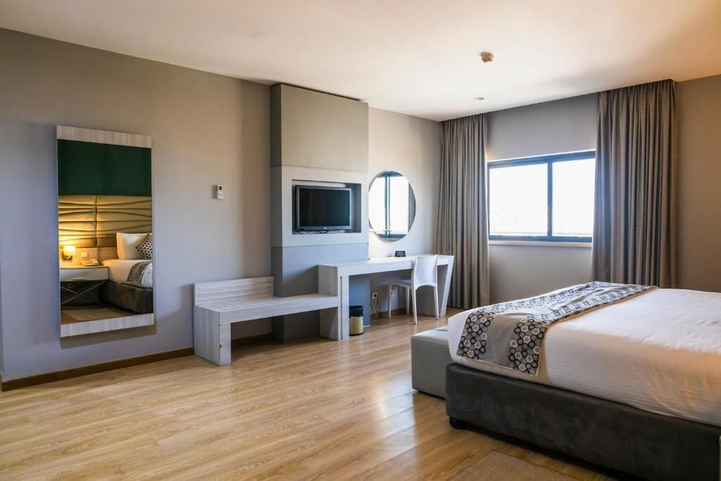 A modern hotel room with a bed, desk, chair, and a television.