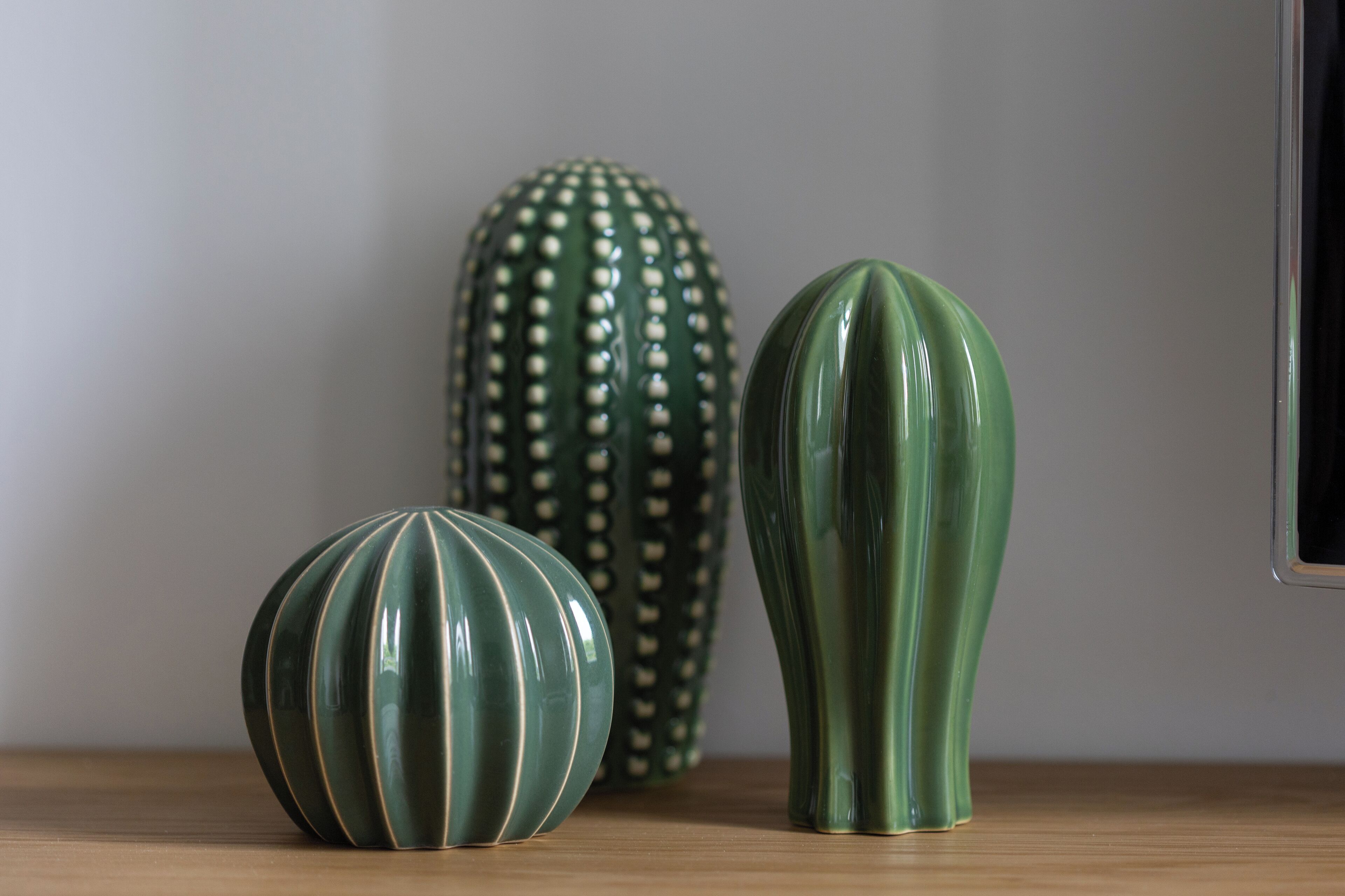 Three green ceramic vases on a wooden surface.