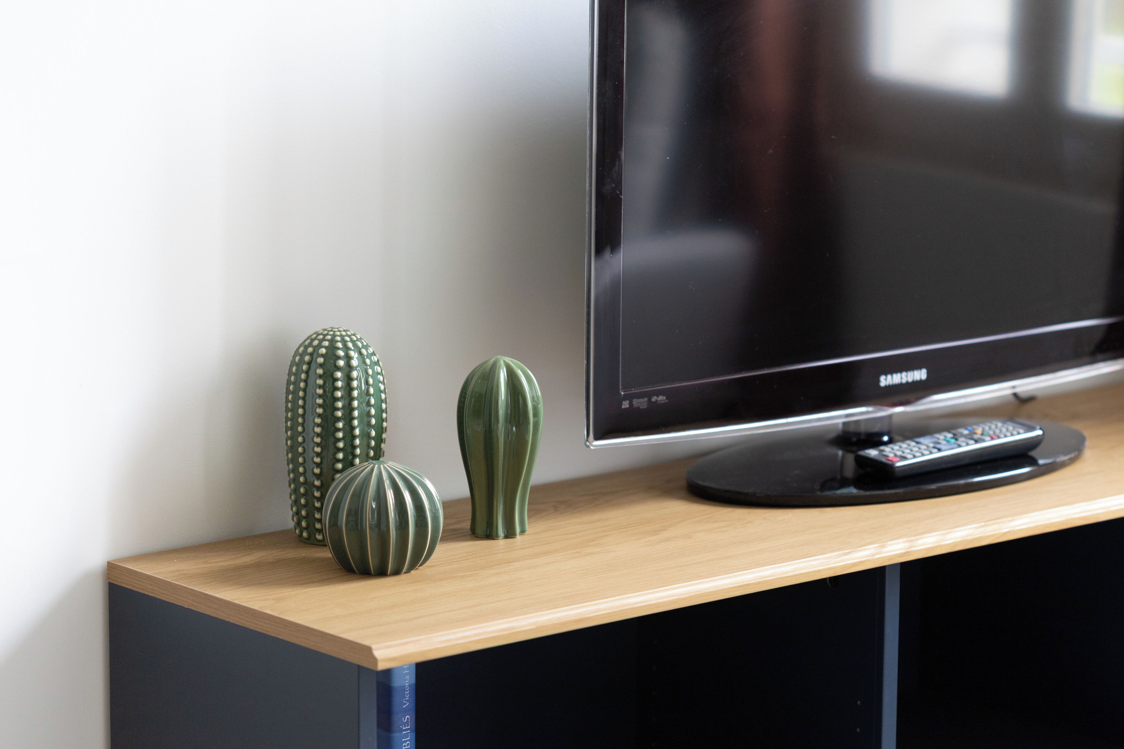 A flat-screen TV on a wooden shelf with three decorative vases.
