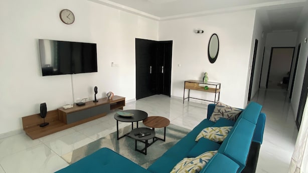 A modern living room with a sofa set, a flat-screen TV, a coffee table, and a small side table. - Elegant 2-bedroom Apartment in Chic Abidjan Neighborhood (Abidjan)