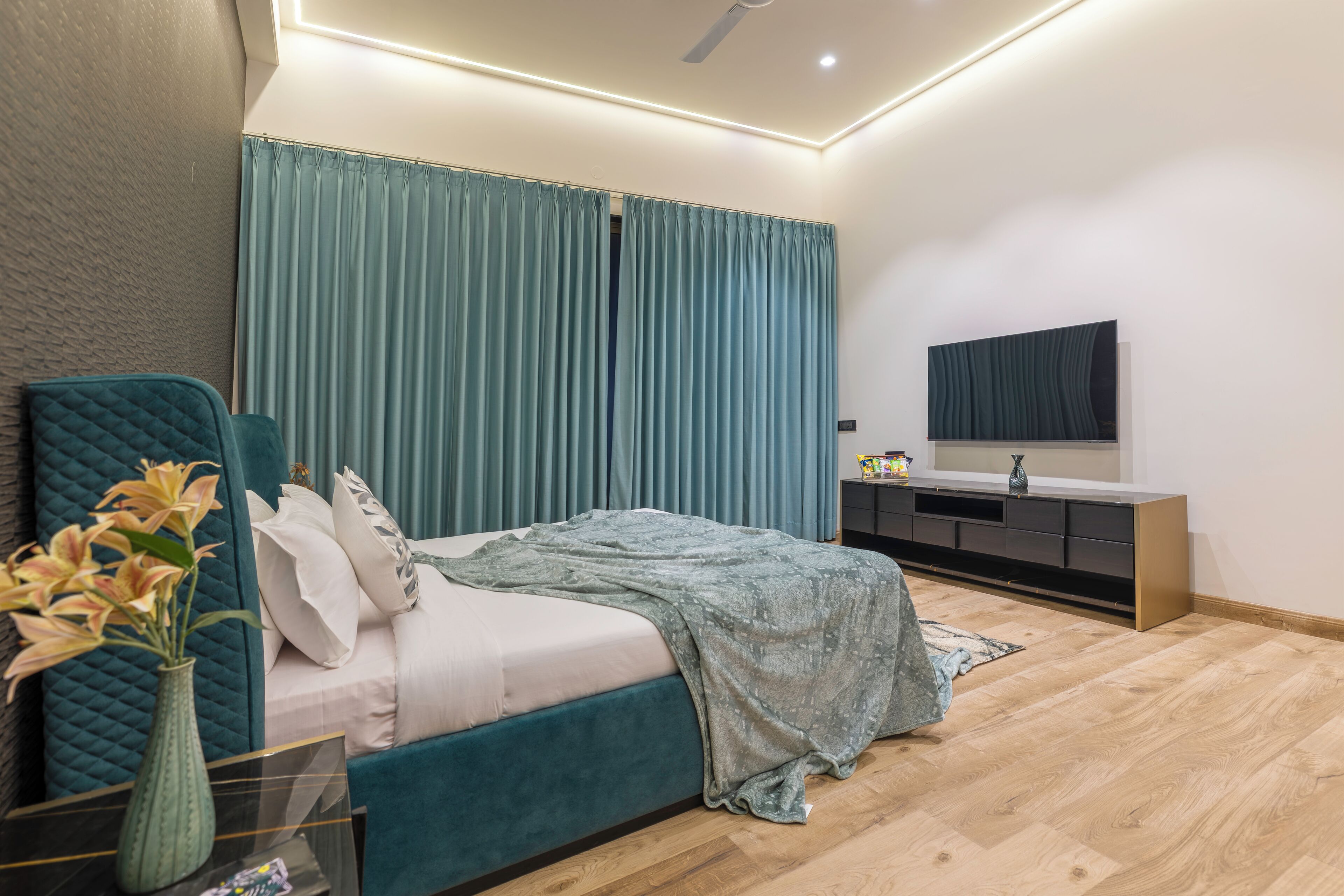 Een moderne slaapkamer met een bed, een kaptafel en een groot raam met gordijnen.