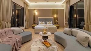 A modern hotel room with a large bed, two sofas, a coffee table, and a ceiling fan. - Elivaas Levante Farms 5 BHK Villa (New Delhi)