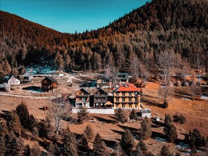 A mountain lodge with multiple cabins and a central building with a red roof, surrounded by dense forest and a clear sky. - Čar Šume Forest Charm (Užice)