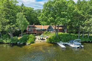 Eine Holzhütte am See mit Steg, Gartenmöbeln und einem Boot.