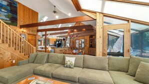 Un interior de madera con un sofá modular, una escalera de madera y una zona de cocina.