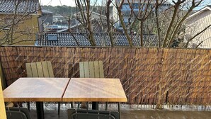 An outdoor patio with a wooden table and metal chairs, a bamboo fence, and a tiled floor. - Apartment in Les Hameaux de l'océan 200m from the ocean (Carcans)