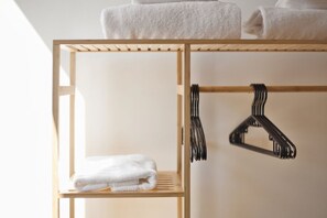 A wooden shelf with a folded white towel and a black hanger. - Hostmate - Milano - Doria's Light - Stazione Centrale (Milan)