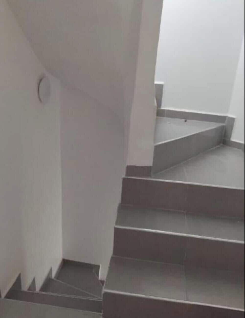 Un escalier avec des marches gris foncé et des murs blancs.