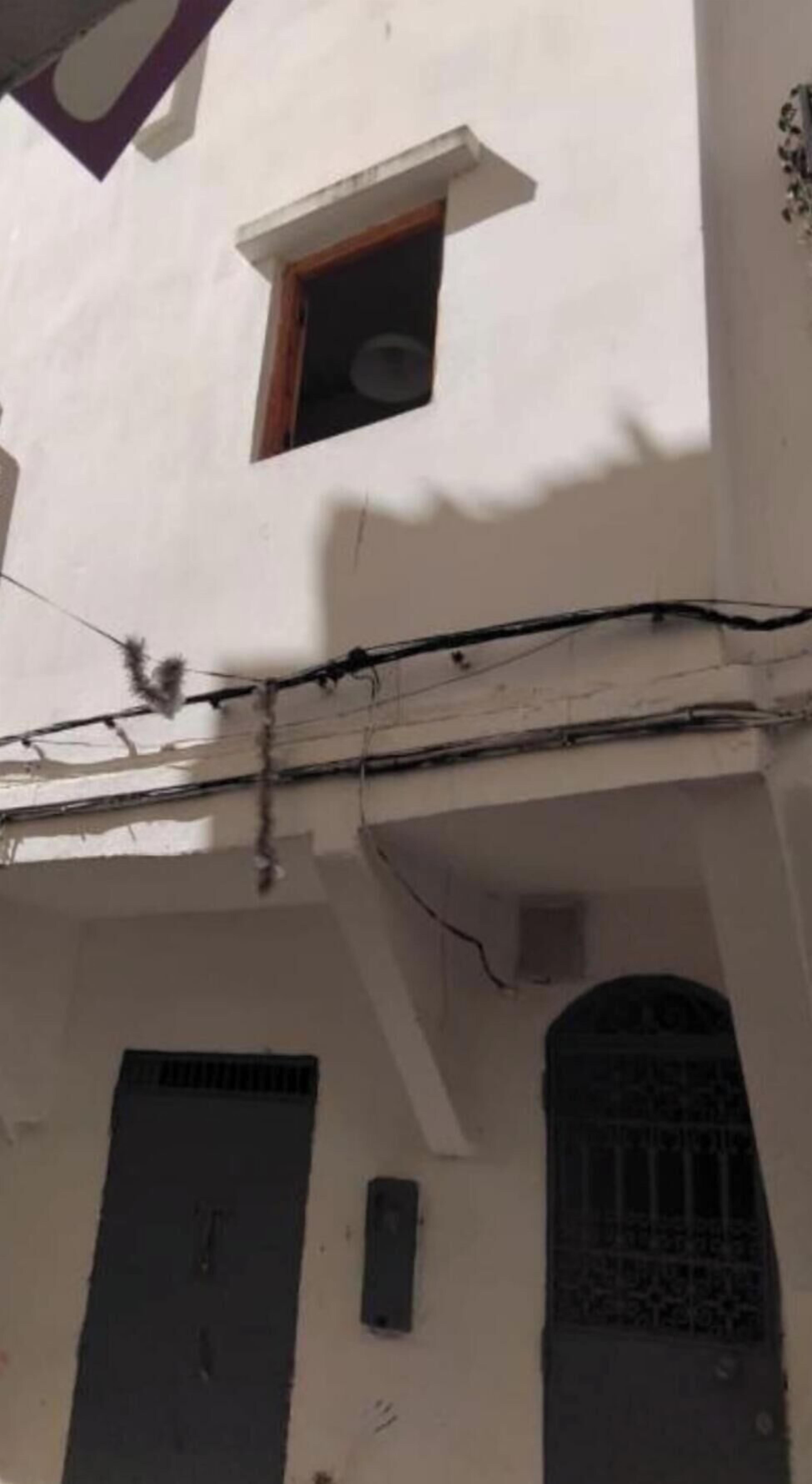 Un bâtiment doté d’une petite fenêtre et d’une porte, avec des câbles électriques apparents et une bouche d’aération.
