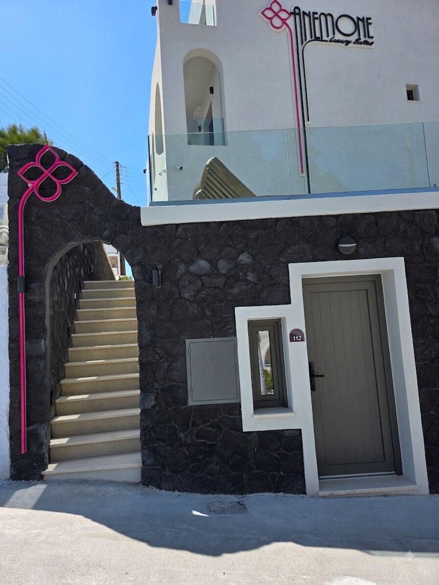 Un bâtiment doté d’une façade en pierre, d’un balcon en verre et d’un escalier menant à l’entrée.