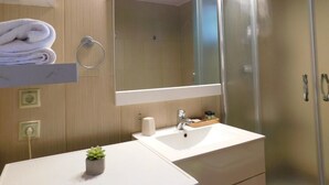 A modern bathroom with a white sink, a mirror, and a glass shower enclosure. - Vassia Holiday Home's (Ermionida)
