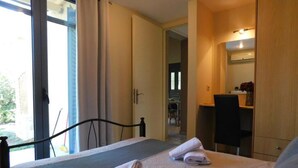 Habitación de hotel con cama, escritorio y silla. Hay toallas sobre la cama y una ventana con cortinas.