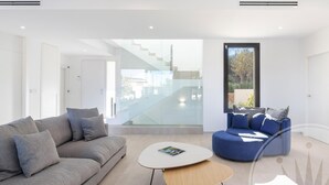Un salon moderne avec un canapé gris, un fauteuil bleu et une table basse ronde.