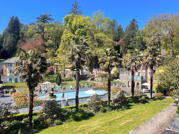 Una piscina rodeada de palmeras y un edificio con jardín.