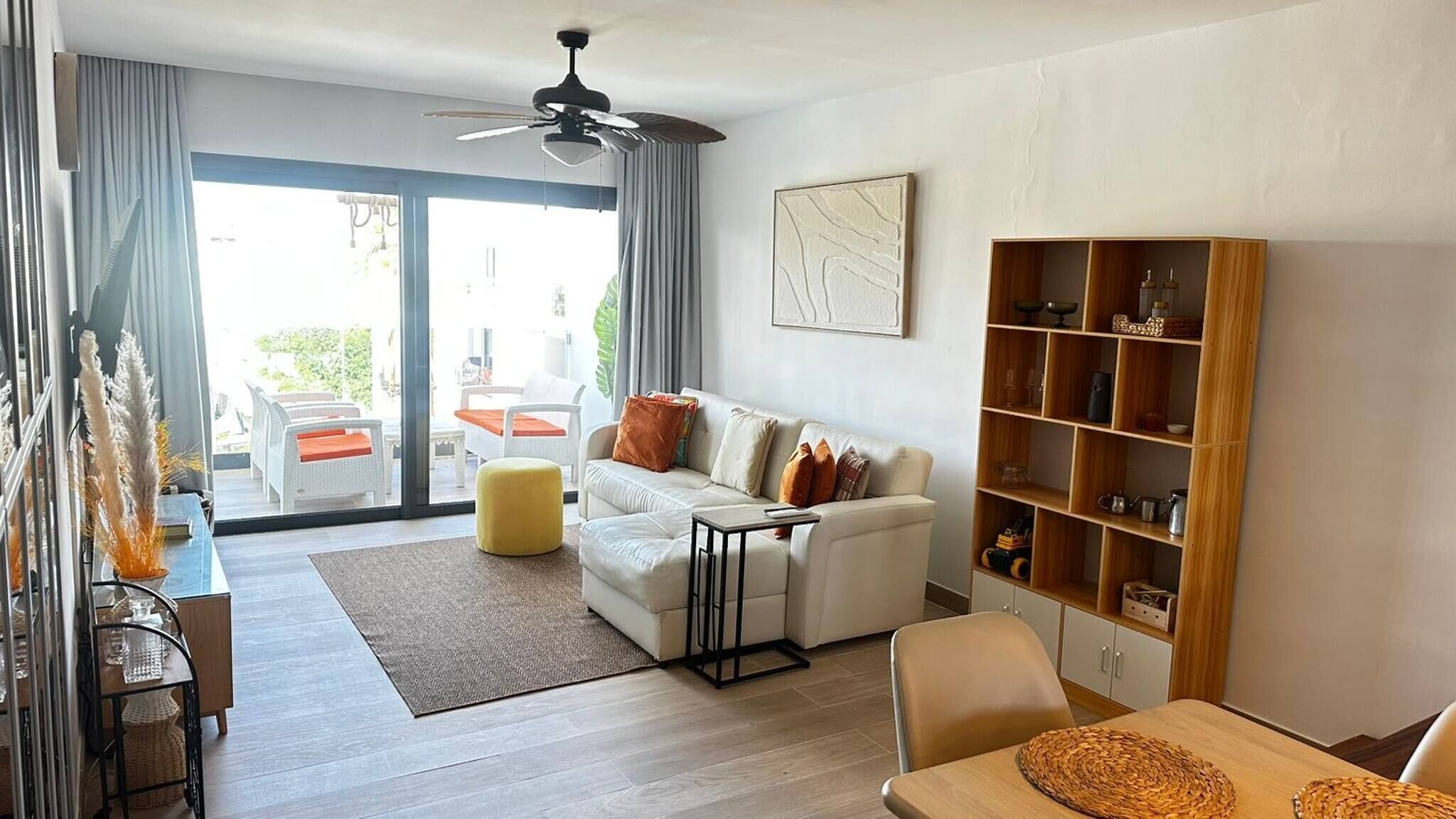 A modern living room with a sofa, ottoman, and a wooden bookshelf.