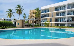 A modern hotel with a pool, palm trees, and a clear sky. - Beautiful Apartment Bavaro Beach (Punta Cana)
