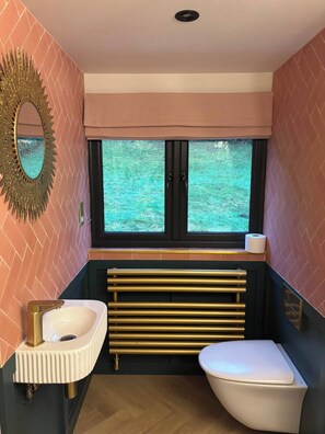 A bathroom with a white sink, a toilet, a window with a view of greenery, and a decorative mirror. - Holly Studio Midhurst (Midhurst)