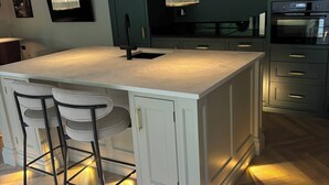 Una cucina moderna con una grande isola, sgabelli da bar e luci a sospensione.