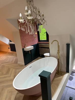 A modern bathroom with a freestanding bathtub, a vanity with a sink, and a chandelier. - Holly Studio Midhurst (Midhurst)