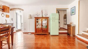 A spacious kitchen with a dining area, a green refrigerator, and a wooden cabinet with glass doors. - Casa Laura - Nature and Art Near Florence (Rufina)