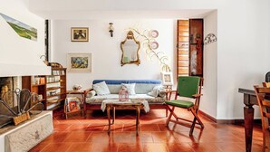 A cozy living room with a sofa, a wooden coffee table, and a green armchair. There are bookshelves, a fireplace, and a mirror on the wall. - Casa Laura - Nature and Art Near Florence (Rufina)