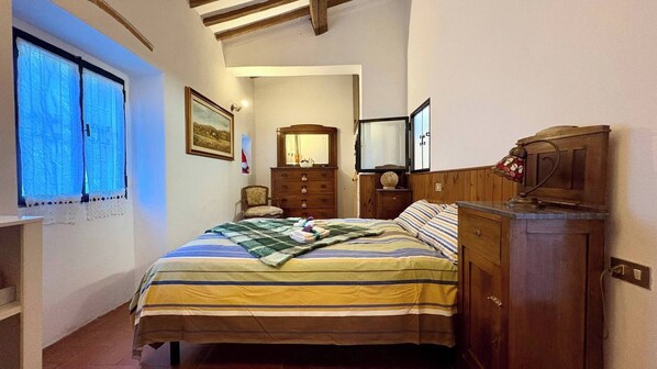 A bedroom with a bed, a dresser, a mirror, and a window with curtains. - Casa Laura - Nature and Art Near Florence (Rufina)