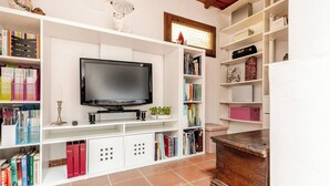 A living room with a flat-screen TV, white shelving units, and a wooden coffee table. - Casa Laura - Nature and Art Near Florence (Rufina)