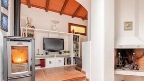 A living room with a fireplace, a television, and a bookshelf. - Casa Laura - Nature and Art Near Florence (Rufina)