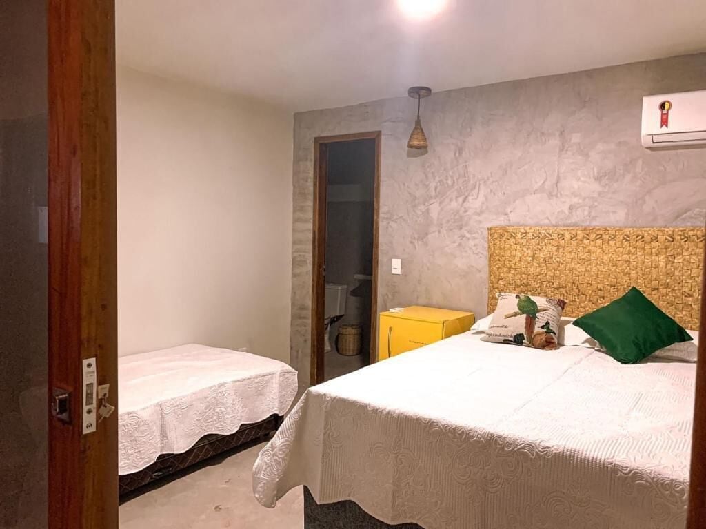 Un dormitorio con dos camas individuales, un cabecero de madera, un caja amarillo y una almohada verde.