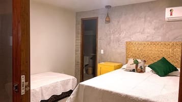 Un dormitorio con dos camas individuales, un cabecero de madera, un caja amarillo y una almohada verde.