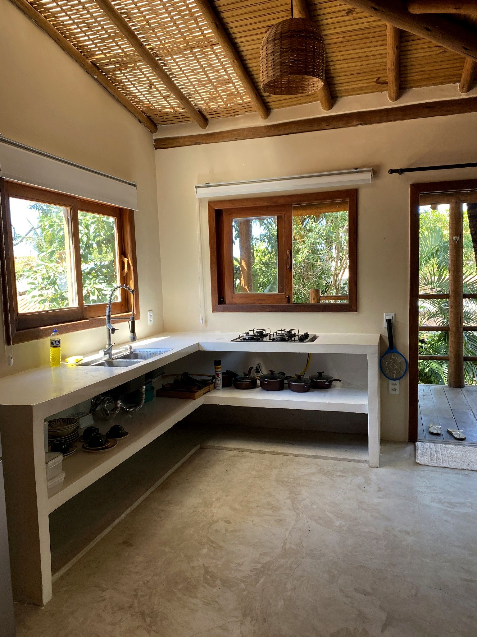 A kitchen with a built-in gas stove, a sink, and a window overlooking greenery.