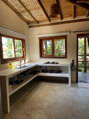 A kitchen with a built-in gas stove, a sink, and a window overlooking greenery.