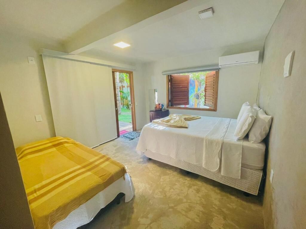 A bedroom with a bed, a bedside table, and a window with blinds.
