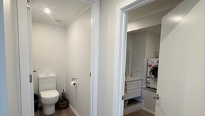 A clean, modern bathroom with a toilet, sink, and washing machine. - Cozy 2-bedroom House Rental in Whangārei, New Zealand (Whangarei)