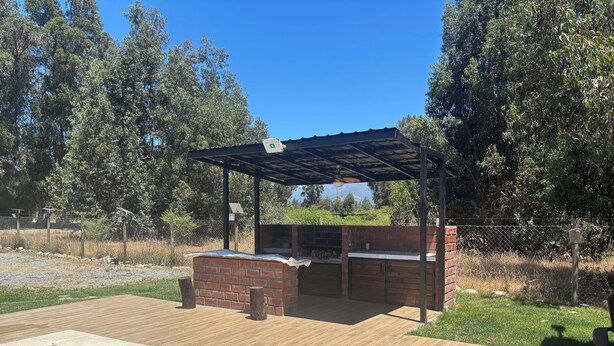 Un patio trasero con área de barbacoa, piscina y terraza de madera.