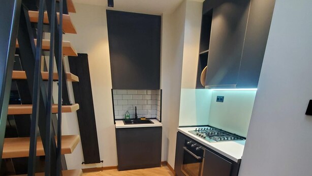 Une cuisine moderne avec un parquet en bois disposé en chevrons, un four encastré et une cuisinière à gaz.