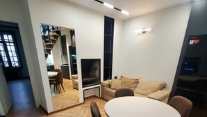 Un salon moderne avec une table ronde et des chaises, un canapé et un téléviseur.