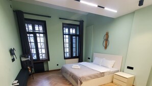 Une chambre à coucher avec un lit, des tables de chevet, une commode et une fenêtre avec des rideaux.