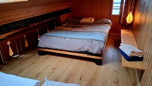 A wooden cabin bedroom with a bed, a bench with towels, and a window. - Lake View Chalet , Därligen (Darligen)
