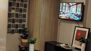 Una sala moderna con un televisor montado en la pared, un panel decorativo con diseño y un cuadro enmarcado.