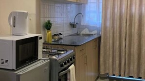 Una cocina compacta con microondas, estufa, pileta y alacenas.