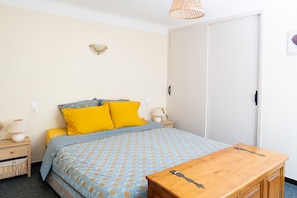 Une chambre à coucher avec un lit, une table de chevet, une lampe et une petite table en bois.