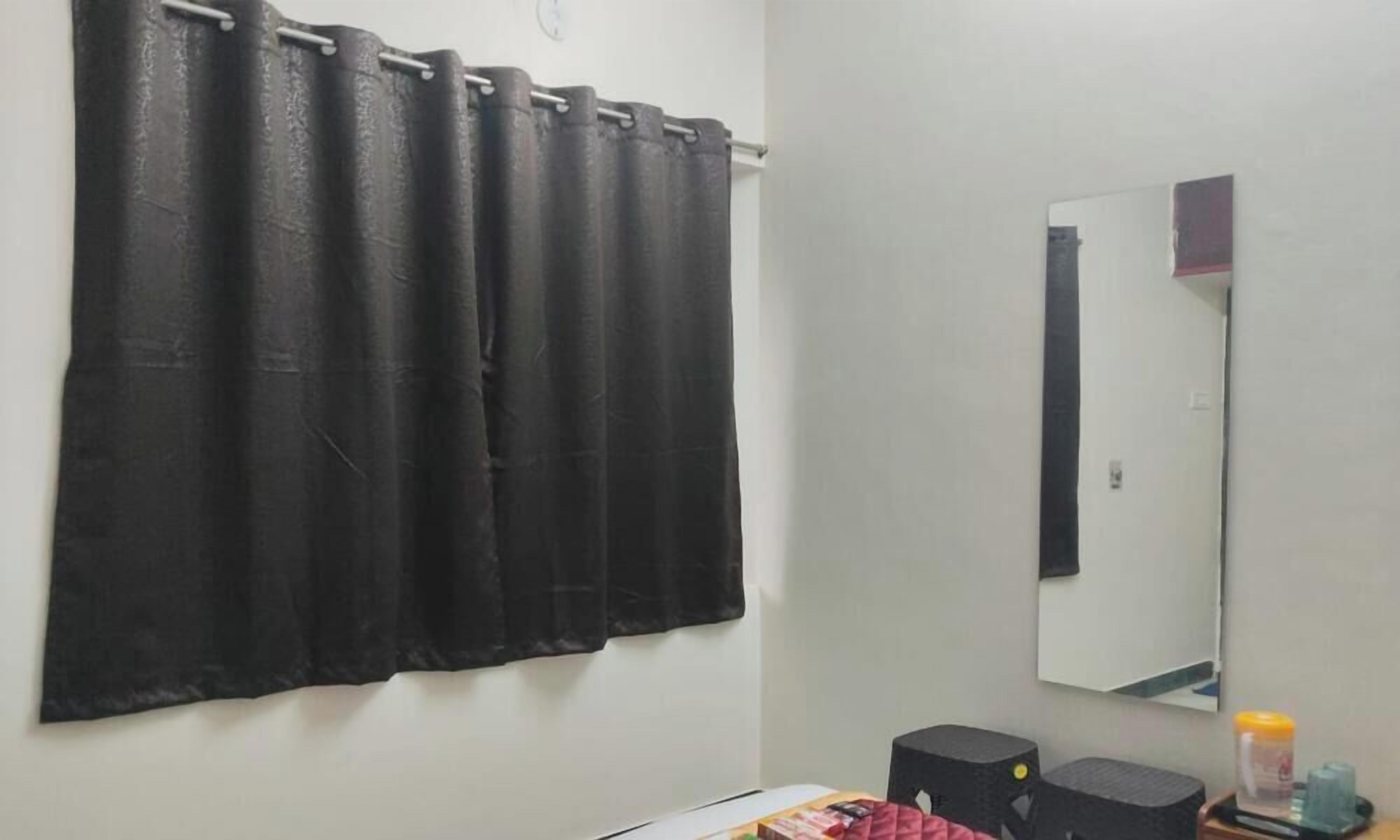 Una habitación con cortina negra, un espejo y dos altavoces negros en la pared.