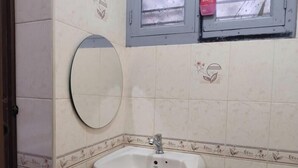 Ein Badezimmer mit rundem Spiegel, Waschbecken und dekorativen Fliesen.