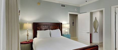 A neatly arranged bedroom with a large bed, a nightstand, a lamp, and a ceiling fan.